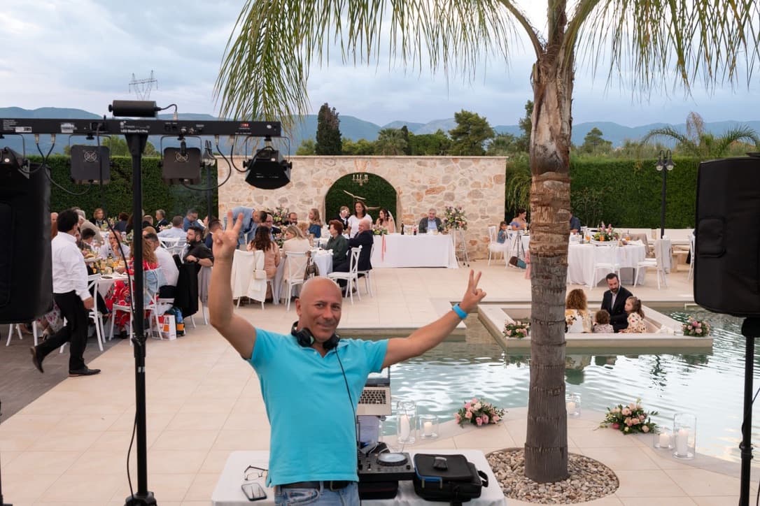 DJ Alex Bedeleu performing at luxury outdoor wedding venue in Zakynthos with pool and mountain views