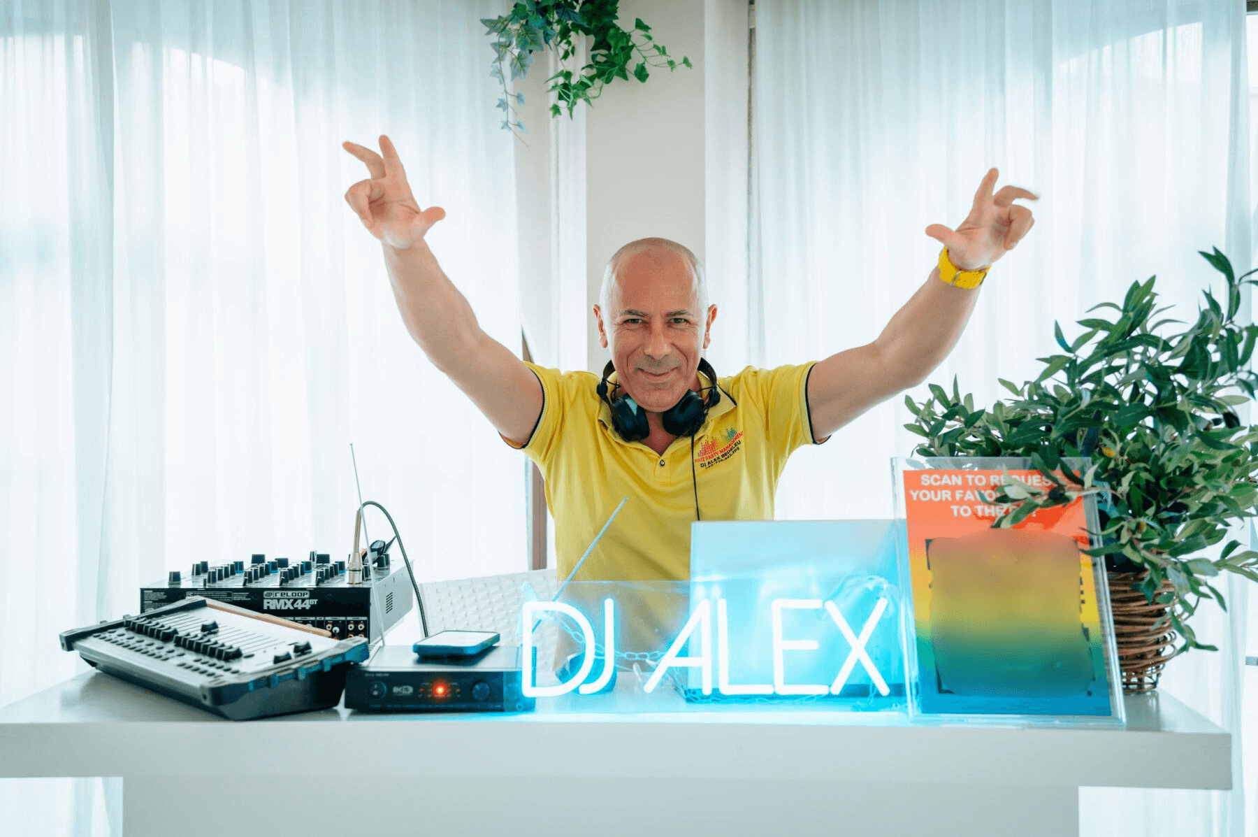 DJ Alex Bedeleu at his DJ booth with neon sign and professional equipment